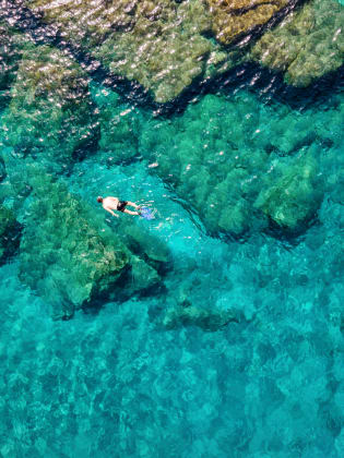 Ein Mann, der im Sommer im smaragdgrünen Wasser der Ägäis auf der griechischen Insel Andros © iStock.com/SHansche