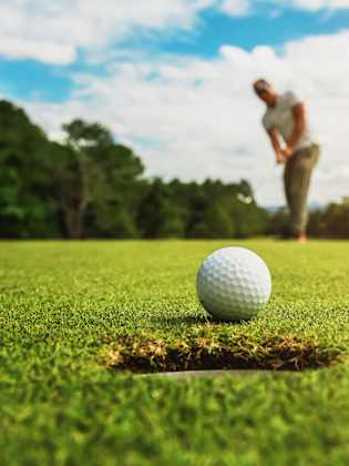 Golfer beim Putt – der Ball kurz vor dem Loch