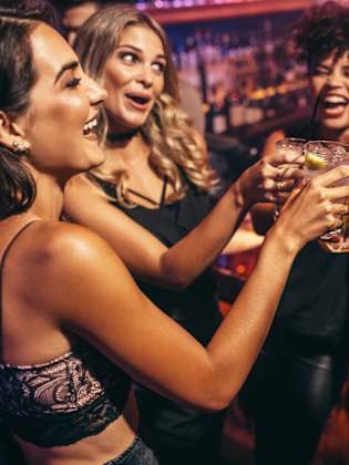 Eine Gruppe von Freunden stößt mit Cocktails in einem Nachtclub an. © jacoblund/iStock / Getty Images Plus via Getty Images
