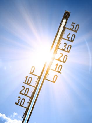 Ein Thermostat vor einem blauen Himmel und strahlender Sonne in der Mitte.