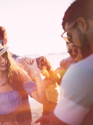 Junge Freunde die Spaß haben bei einer Strandparty bei Sonnenuntergang © iStock.com/wundervisuals