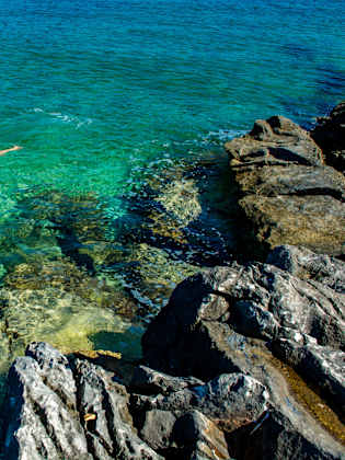 Junges Mädchen schnorchelt durch türkisfarbenes Wasser an der Küste © iStock.com/grafxart8888