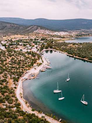 Luftaufnahme einer kleinen Küstenstadt und Segelbooten im Meer © iStock.com/AegeanBlue