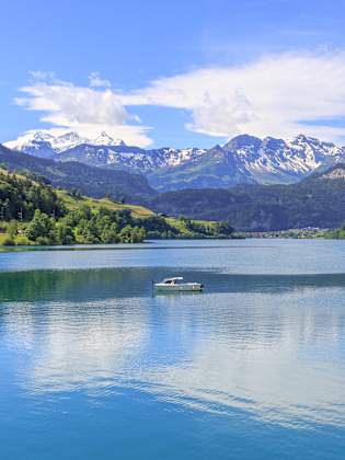 See mit Boot und Bergen im Hintergrund