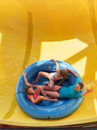 Mädchen fahren in einem Ring auf einer Wasserrutsche. © Sebastian Condrea/Moment via Getty Images