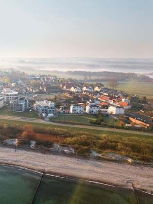 Drohnenaufnahme Strand und Städtchen im Nebel von oben.