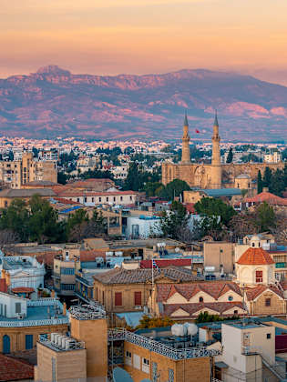 Blick auf eine Stadt mit historischen Gebäuden mit Bergen im Hintergrund