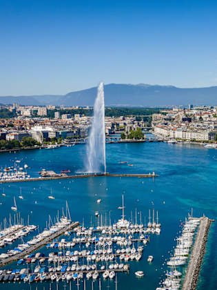 Blick auf Genf am Genfersee mit den Bergen im Hintergrund.