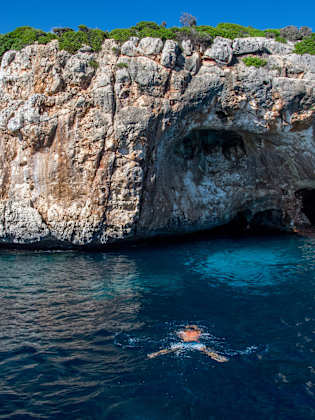 Person taucht zu einer Höhle an der Küste Mallorcas im Mittelmeer © iStock.com/Thomas Bernd