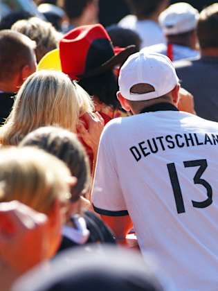 Fans in Deutschlandtrikots sitzen draußen beim Public Viewing