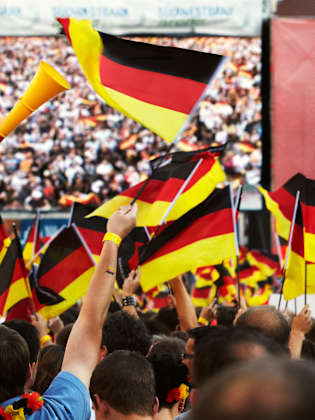 Fans mit Deutschlandflaggen vor einem großen Bildschirm