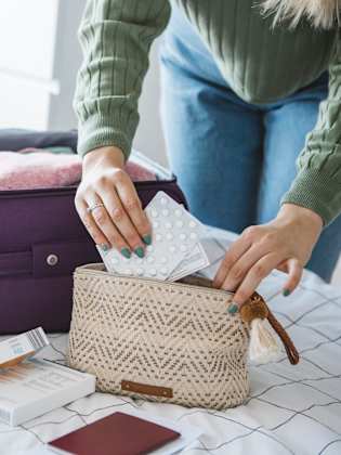 Checkliste für die Reiseapotheke: Eine Frau packt wichtige Medikamente in ihre Reiseapotheke. ©petrunjela/iStock
