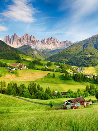 Schönes Bergpanorama mit den Dolomiten im Hintergrund und Hütten in grünem Tal © iStock.com/TomasSereda
