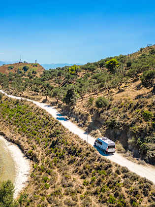 Campervan fährt auf einer Straße am Meer