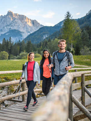 Zwei Frauen und ein Mann laufen über eine Brücke © iStock.com/AzmanL