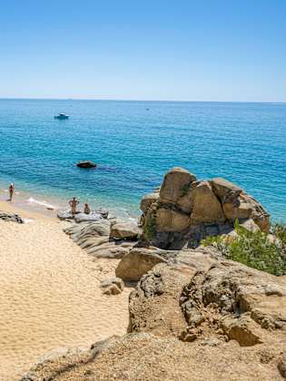Menschen entspannen an einem Strand zwischen Felsen.