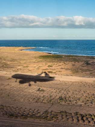 Der Schatten eines Flugzeugs über einer Küste.