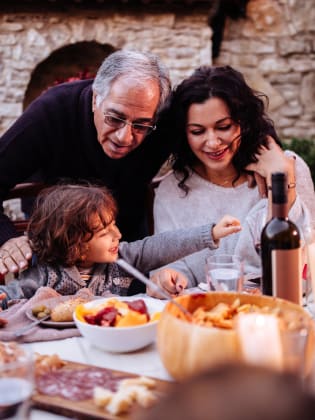 Ein Mann mit seiner Tochter und seinem Enkel beim Essen in Italien. © wundervisuals/E+ via Getty Images
