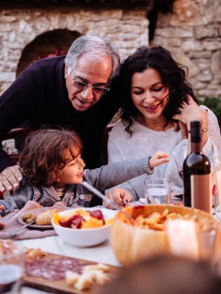 Ein Mann mit seiner Tochter und seinem Enkel beim Essen in Italien. © wundervisuals/E+ via Getty Images