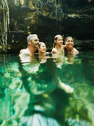 Eine Familie badet in einer Cenote in Mexico.