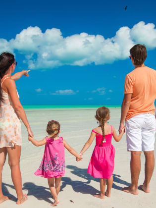 Eine Familie steht an einem Strand und blickt auf das Meer.