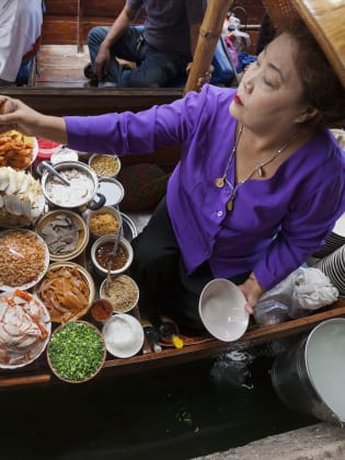 Eine Frau kocht in einem schwimmenden Markt in Thailand. © enviromantic/E+ via Getty Images