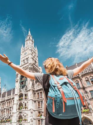Eine Frau mit einem Rucksack steht vor dem Münchner Rathaus.