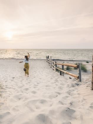 Eine Frau rennt einen Strand in Mecklenburg-Vorpommern, Deutschland, entlang. © Francesco Vaninetti Photo/Moment via Getty Images