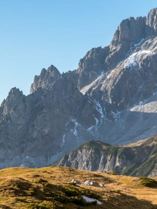 Eine Frau wandert auf einem Weg vor den Bergen in Salzburg, Österreich.