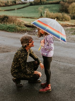 Eine Großmutter kniet vor ihrer Enkelin, die einen Regenschirm hält. © Catherine Falls Commercial/Moment via Getty Images