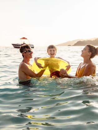 Eine Familie planscht glücklich im Meer.