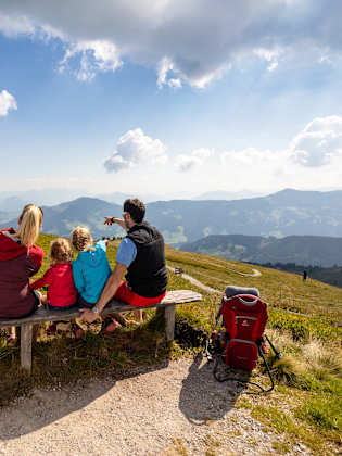 Eine Familie sitzt auf einer Bank und schaut ins Tal.