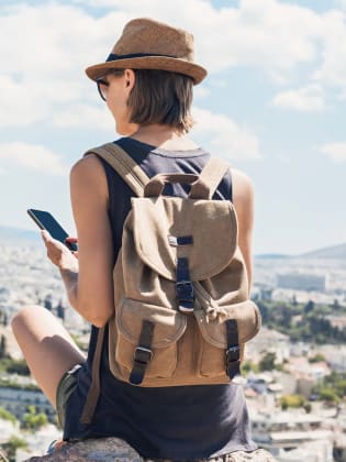 Eine Frau mit ihrem Smartphone vor Ruinen in Athen.