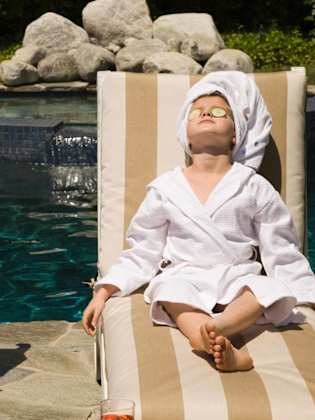 Frau und Kind entspannen mit einer Gurkenmaske im Gesicht am Pool.
