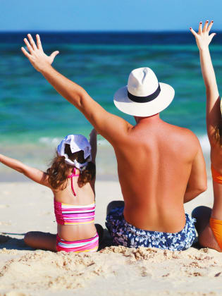 glückliche Familie mit Vater Mutter und Kindern sitzen am Strand © iStock.com/evgenyatamanenko