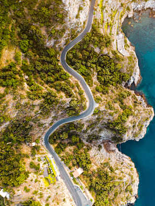 Dronenblick auf die Küstenstraße und tiefblaues Meer an der Amalfiküste, Italien. © Marco Bottigelli via Getty Images