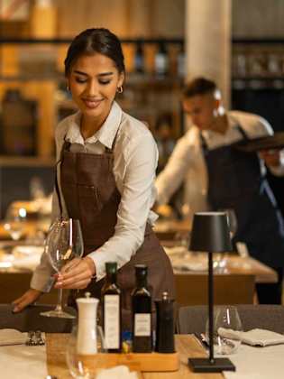 Eine Kellnerin deckt einen Tisch in einem Restaurant.