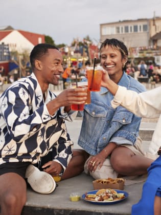 Junge Menschen stoßen mit einem Cocktail an.