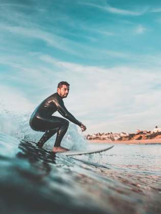 junger Mann surft auf einer Welle vor der Küste © iStock.com/Raul_Mellado