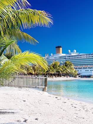 Kreuzfahrtschiff an einem Srand mit türkisem Wasser
