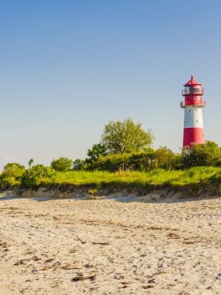 Ein Leuchtturm an einem Strand in Schleswig-Holstein, Deutschland. © Westend61/Westend61 via Getty Images