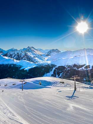 Blick auf einen Skilift zwischen verschneiten Bergen