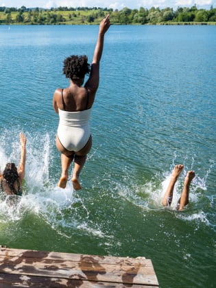 Mehrere Personen springen in das Wasser eines Sees