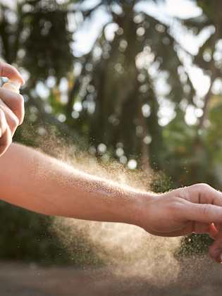 Eine Person sprüht ein Spray auf ihren Arm.