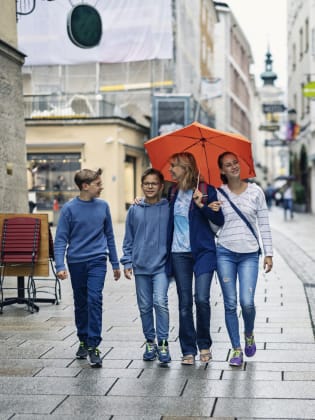 Eine Mutter läuft mit ihren Kindern im Regen durch Salzburg, Österreich. © Imgorthand/E+ via Getty Images
