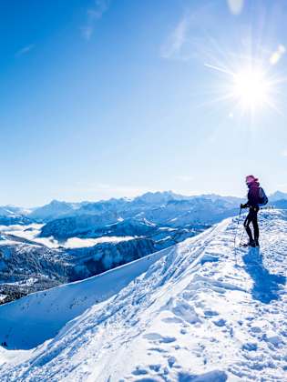 Ein Wanderer steht vor einer Schweizer Fahne auf einem Berg in den Alpen.