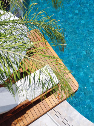 Liegen unter Palmen am blauen Hotelpool.