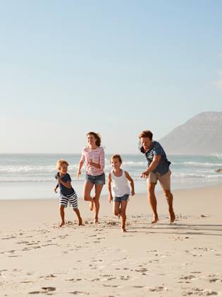 Eine Familie rennt am Strand entlang.