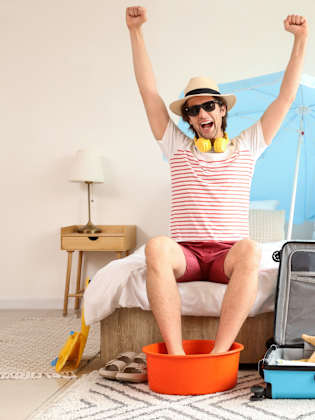 Glücklicher Urlauber mit Koffer im Schlafzimmer © shutterstock_2465436107