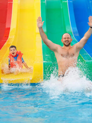 Vater und Sohn haben Spaß auf einer Wasserrutsche.